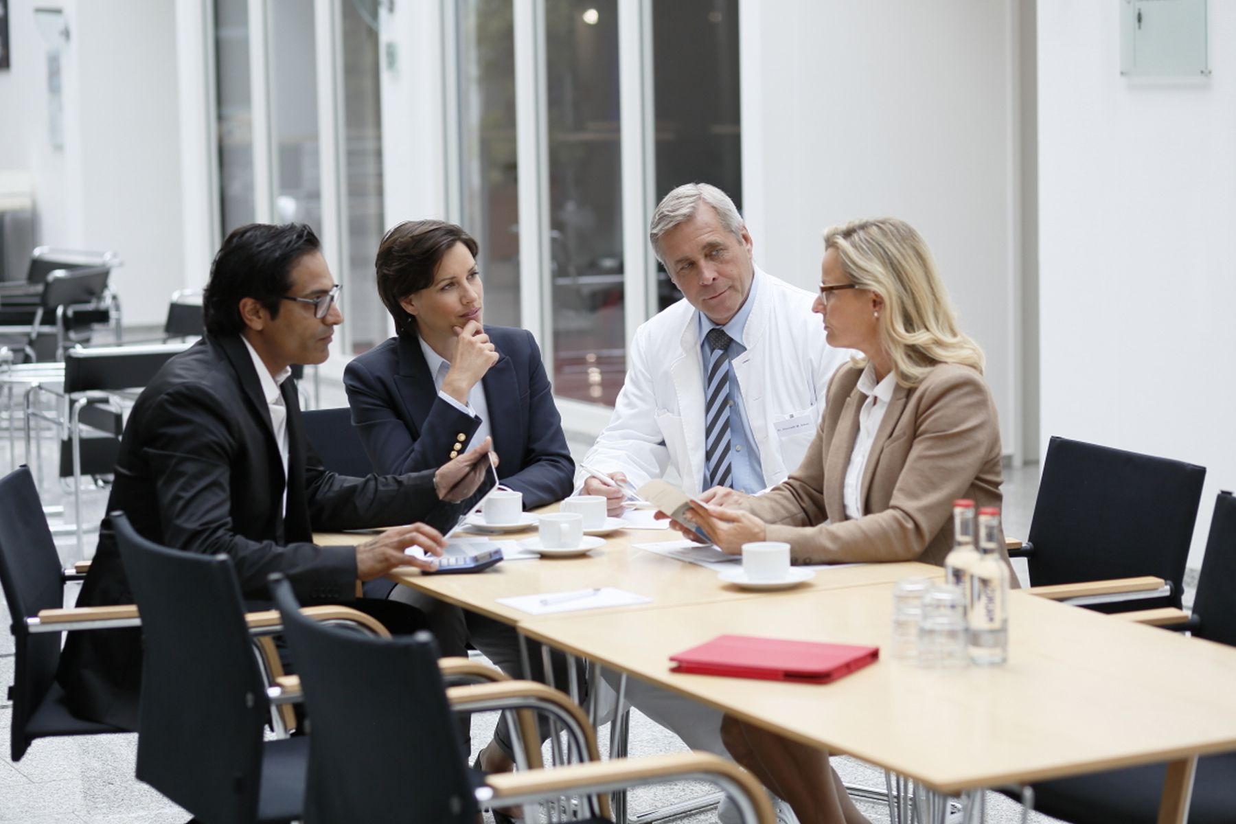foto of 4 professionals sitting at a table talking business and calculating costs
