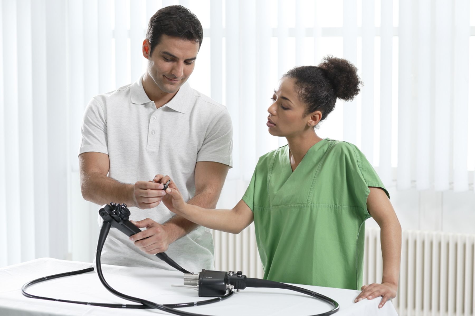 foto of a technician explaining an endoscope to nurse in green scrubs