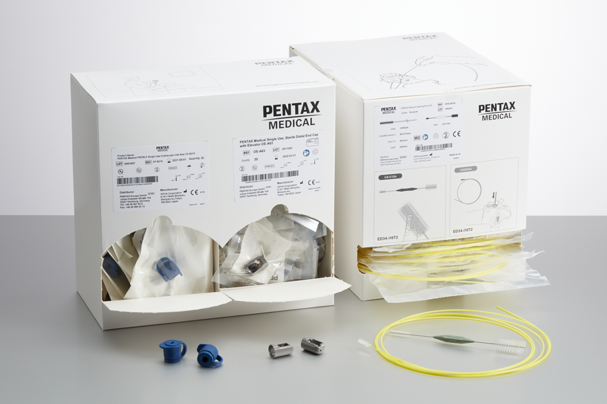 two white boxes with the PENTAX Medical logo on the top left of each. The left box contains blue caps and distal tips, the right contains single use brushes for cleaning